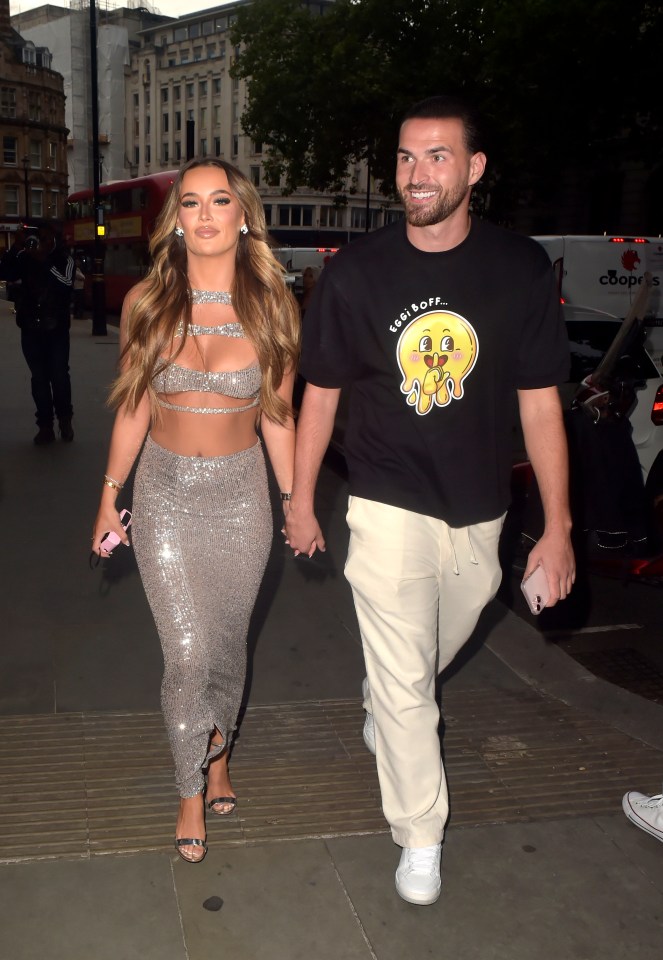 a man wearing a black shirt with a smiley face on it walks with a woman