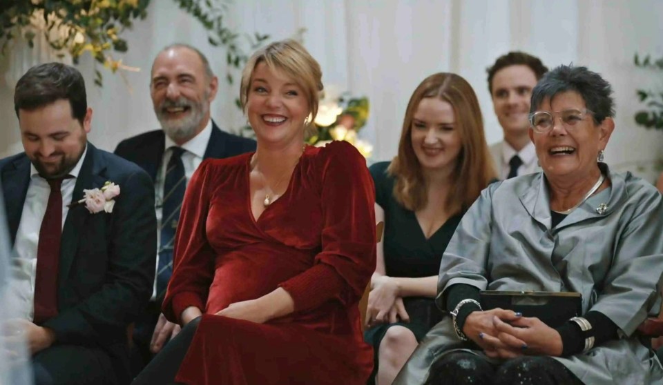 a woman in a red dress is laughing with other people