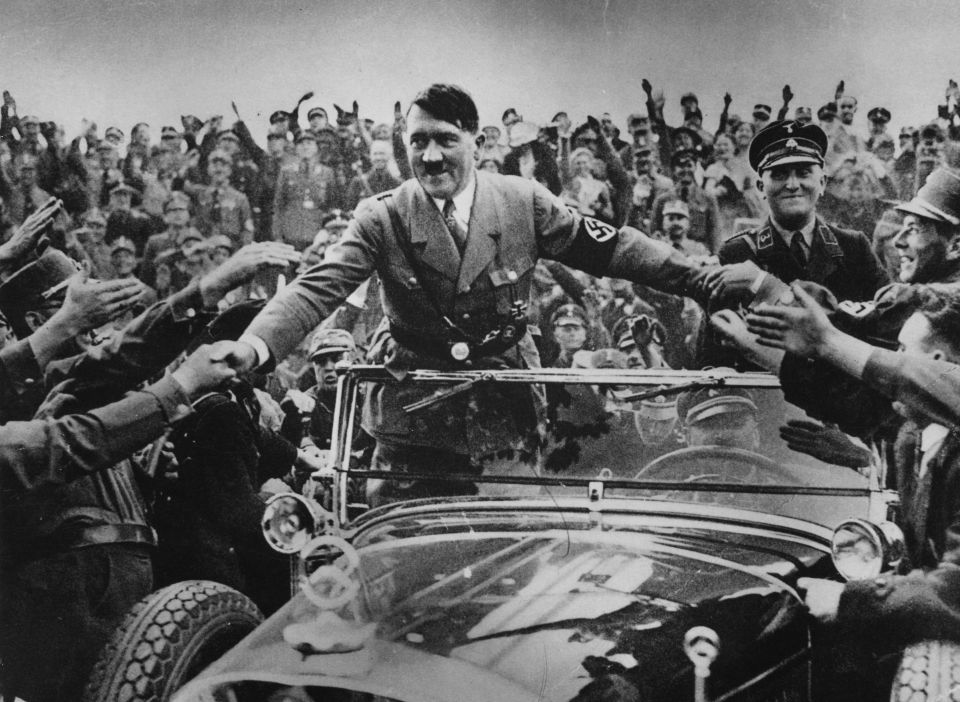 a black and white photo of a man in a car surrounded by people