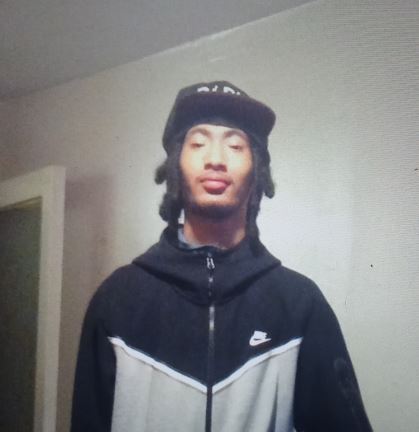 a man wearing a hat and a nike jacket is standing in a room .