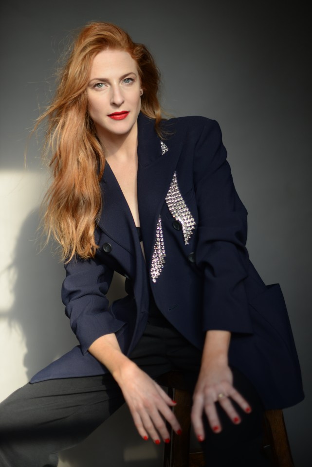 a woman with red hair is wearing a blue jacket with rhinestones on it