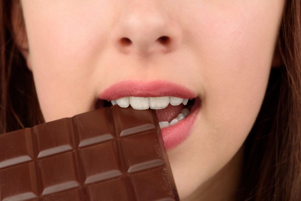a woman is biting into a bar of chocolate