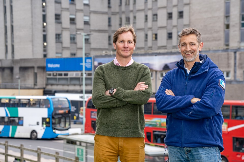 two men standing in front of a building that says welcome