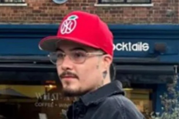 a man wearing a red hat is standing in front of a restaurant called cocktails