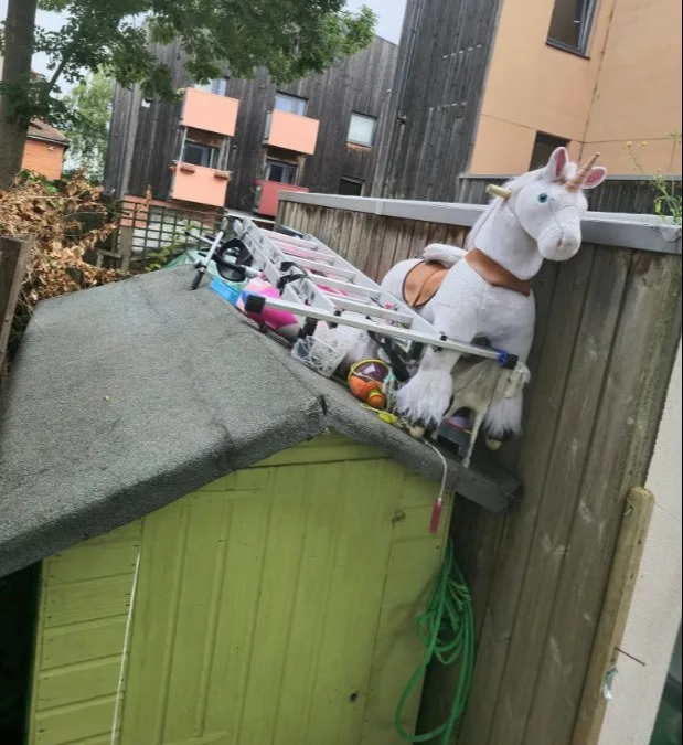 a stuffed unicorn is sitting on top of a green shed