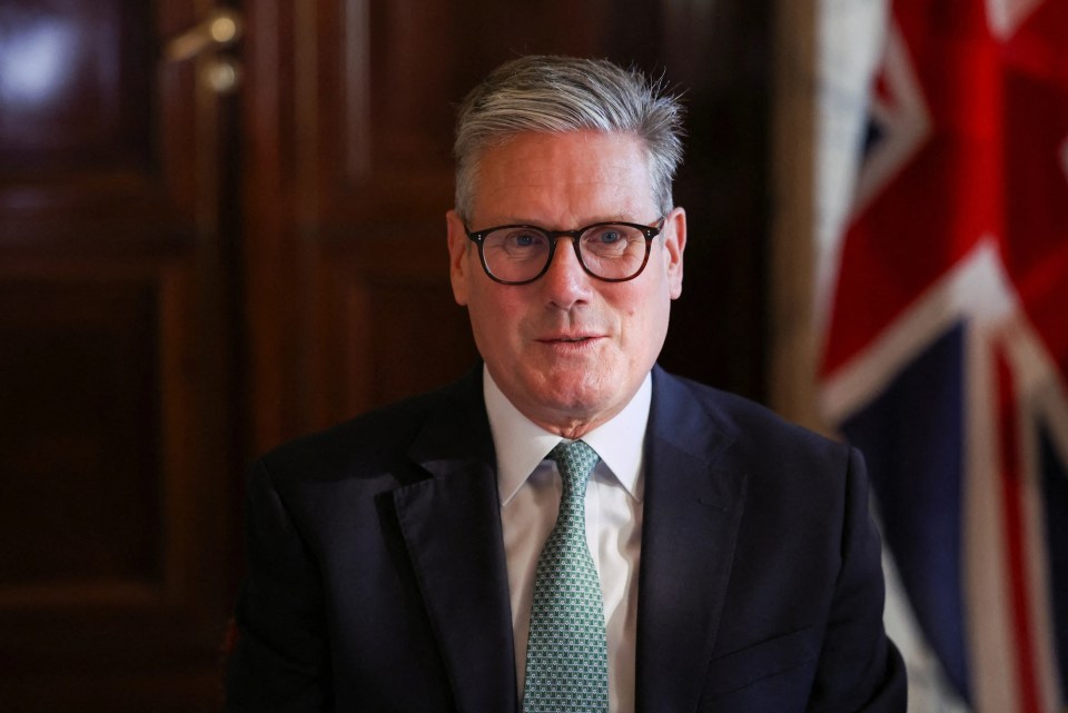 a man in a suit and tie stands in front of a flag