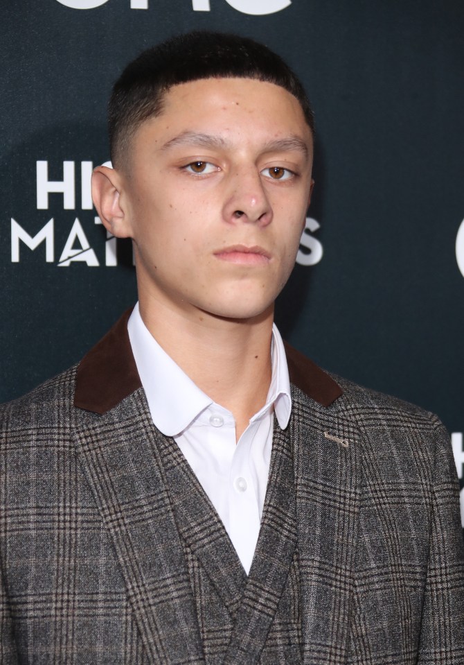 a man in a suit stands in front of a sign that says his masters
