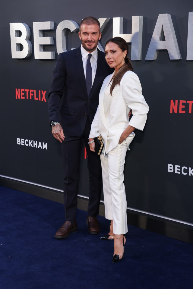 a man and woman are standing in front of a sign that says beckham