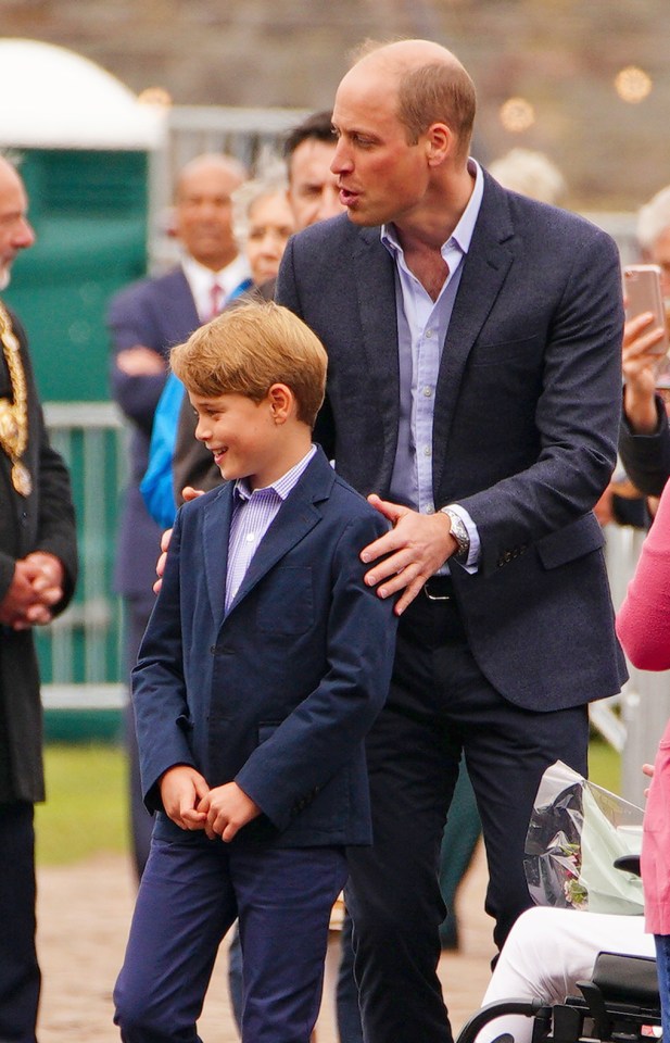 a man in a suit stands next to a boy in a suit