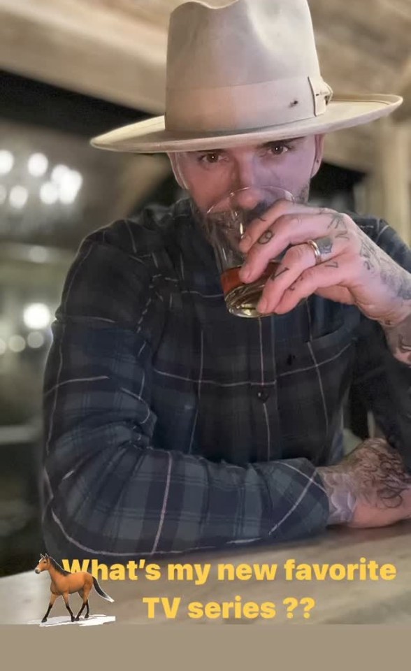 a man in a hat is drinking a glass of whiskey