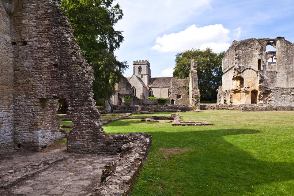the ruins of an old building with a church in the background