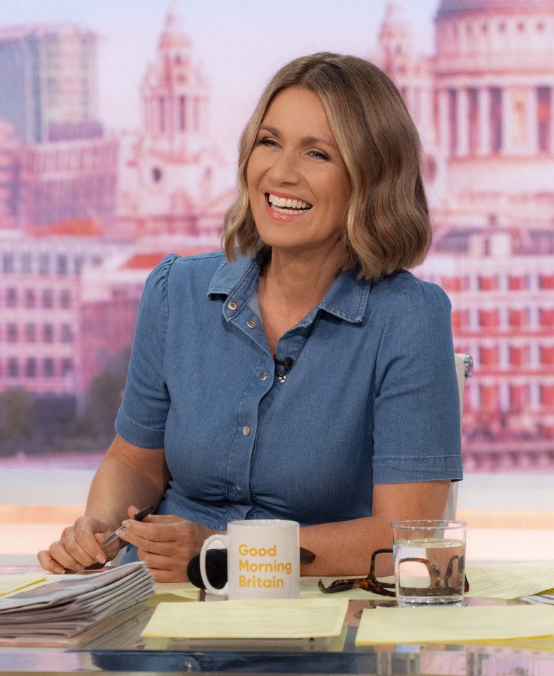 a woman sits at a desk with a mug that says good morning britain