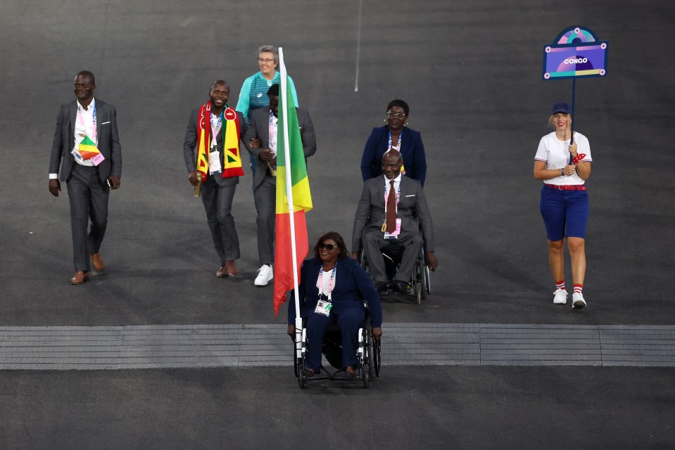 a woman in a wheelchair is carrying a flag at a parade