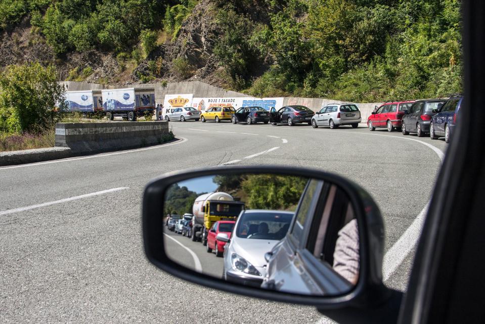 a rear view mirror shows a line of cars going down a road