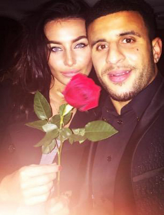 a man and a woman are posing for a picture while the woman is holding a red rose .