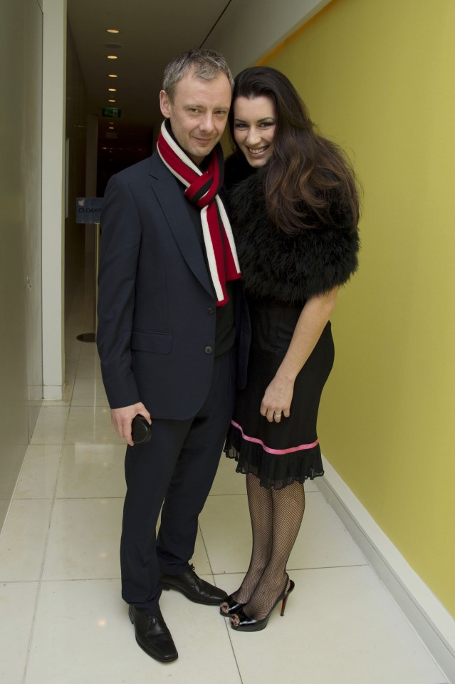a man in a suit and a woman in a black dress pose for a photo
