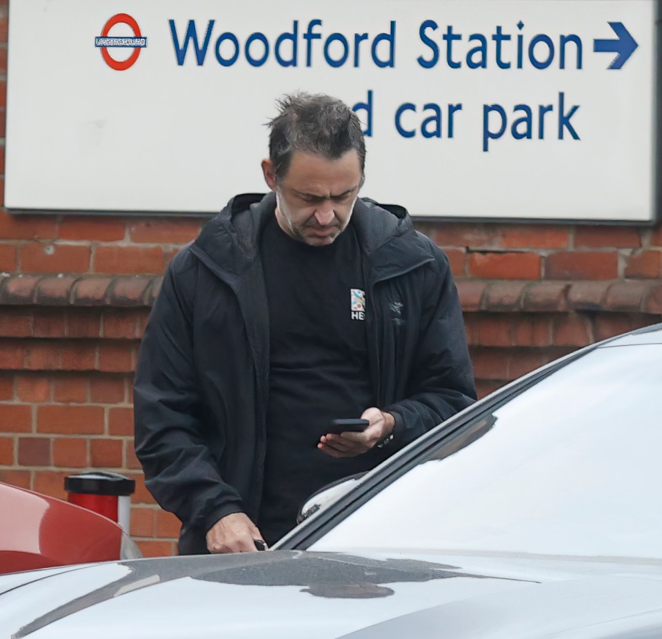 a man stands in front of a woodford station sign