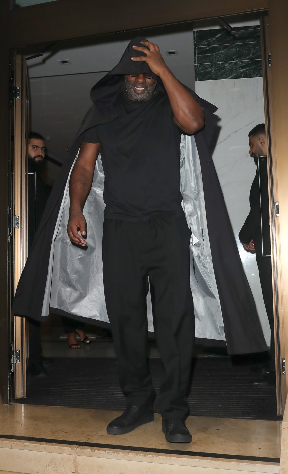 a man in a black coat covering his face