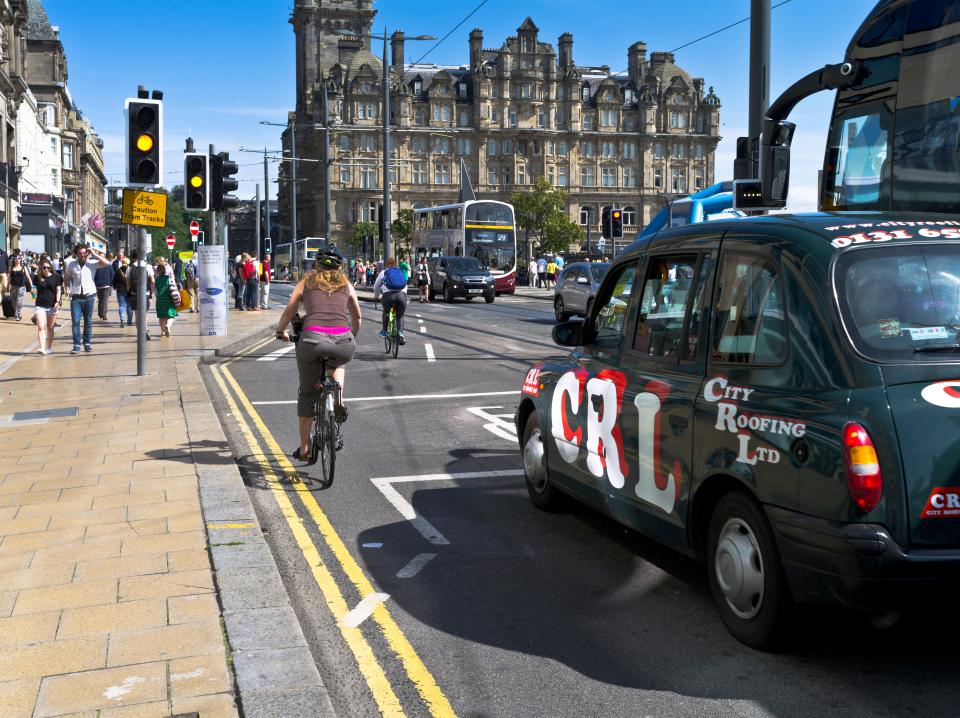 a woman riding a bike next to a city roofing ltd taxi