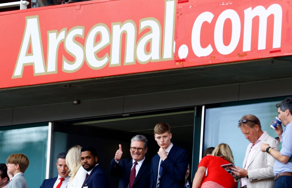 a group of people sitting under a sign that says arsenal.com