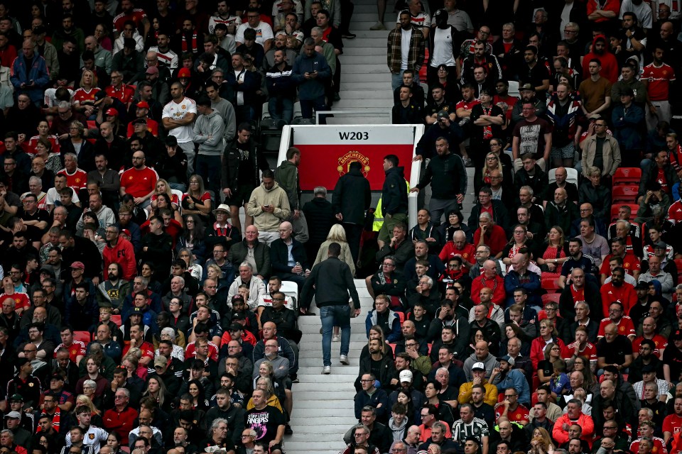 a crowd of people holding a banner that says 12 months the clock is ticking glazers out