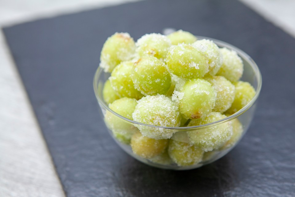 a glass bowl filled with green grapes covered in sugar