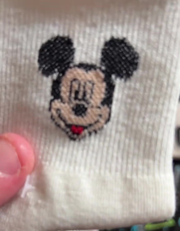 a person is holding a white socks with a mickey mouse embroidered on it