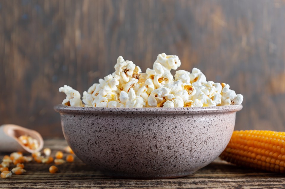 a bowl of popcorn sits on a wooden table