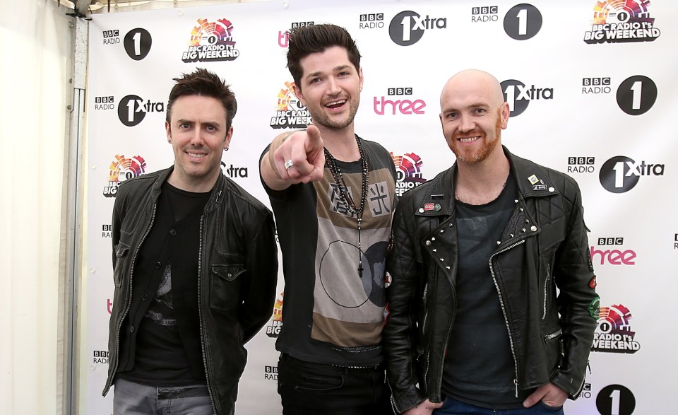three men standing in front of a bbc extra banner