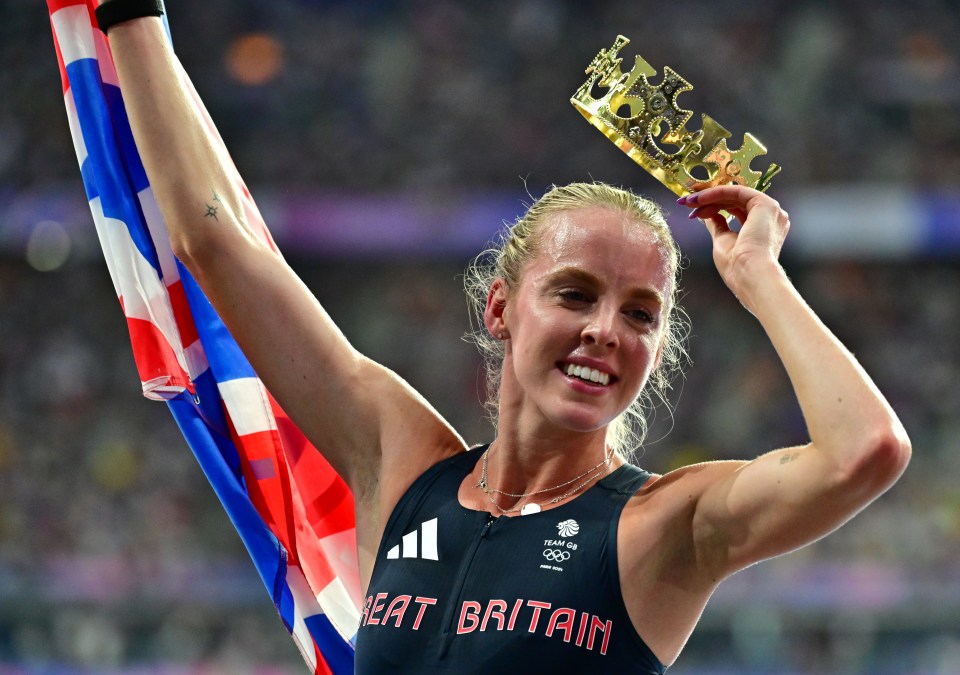 a woman wearing a great britain shirt holds a crown over her head