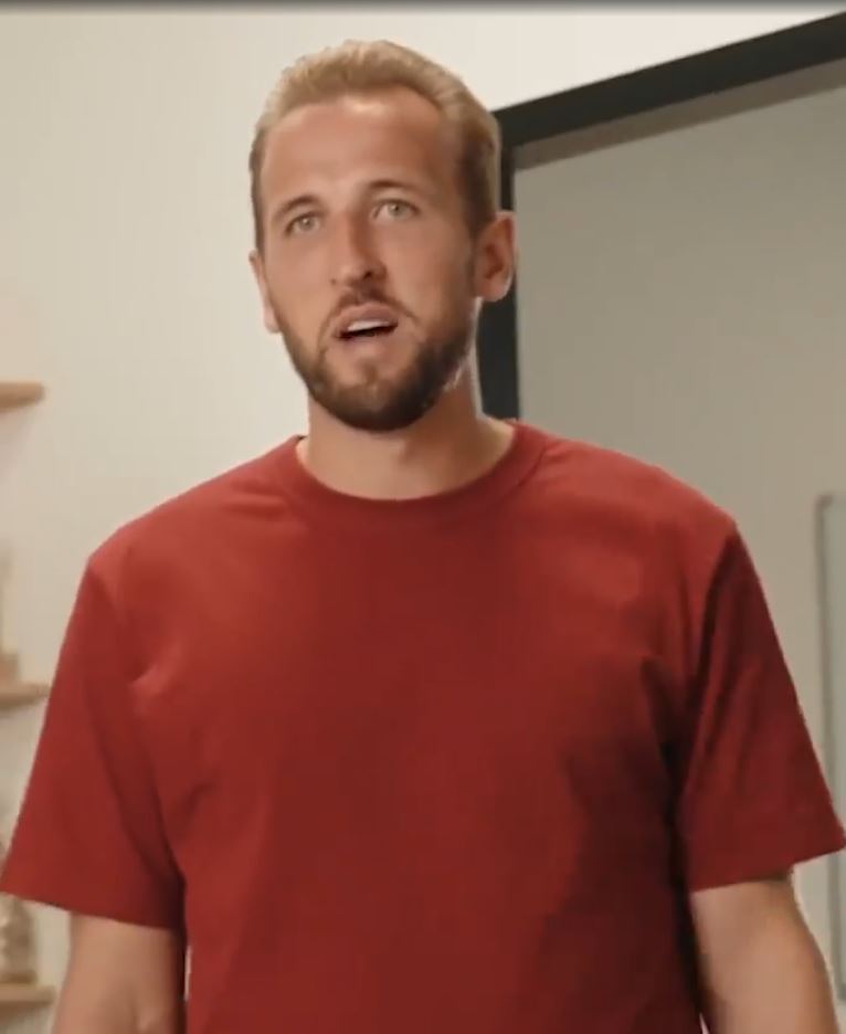 a man with a beard is wearing a red t-shirt and standing in a room .