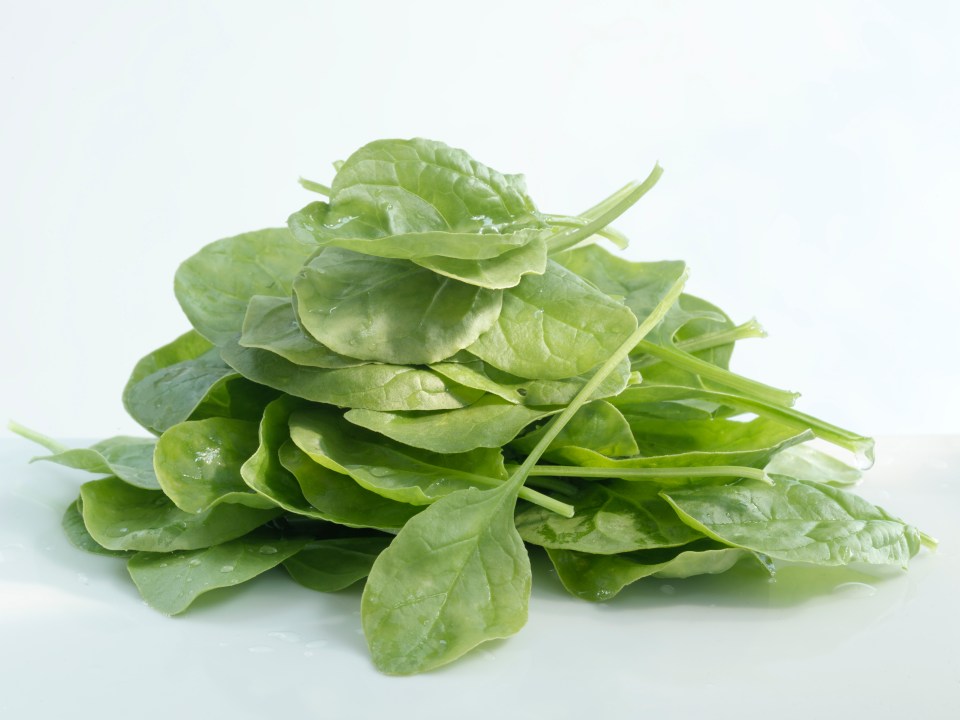 a pile of spinach leaves on a white surface