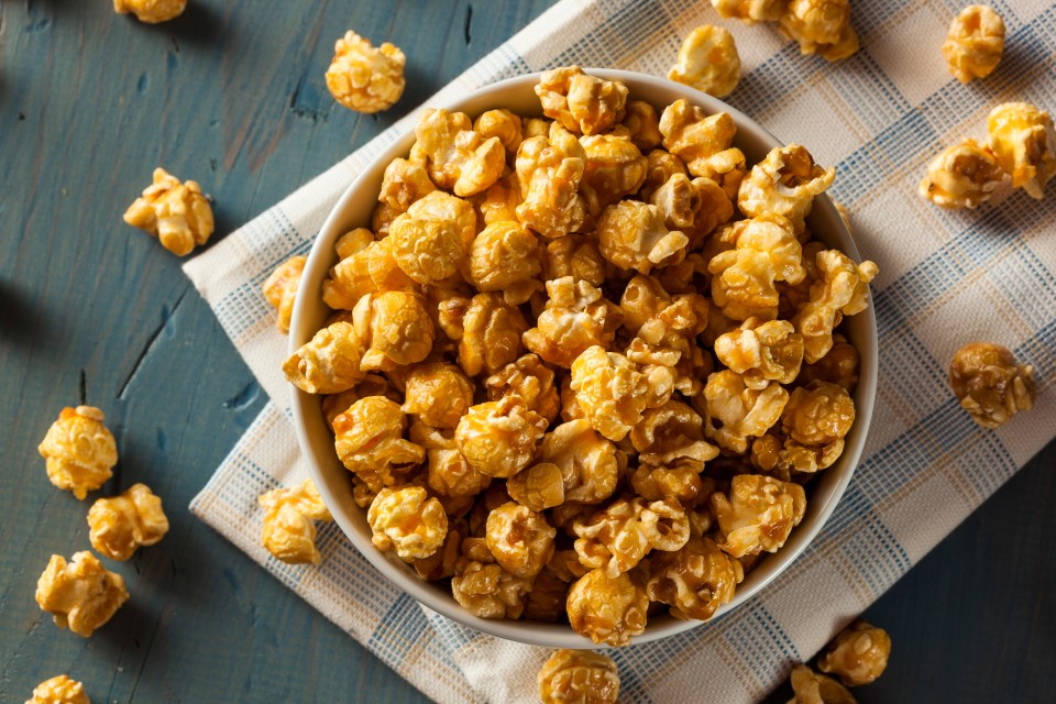 a bowl of caramel popcorn sits on a table