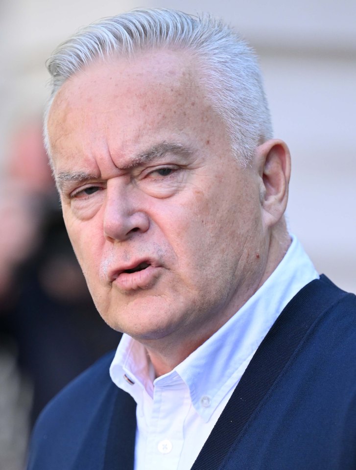 a man with gray hair is wearing a blue jacket and a white shirt