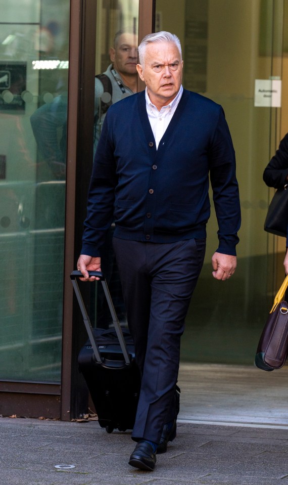 a man in a blue cardigan is pulling a suitcase