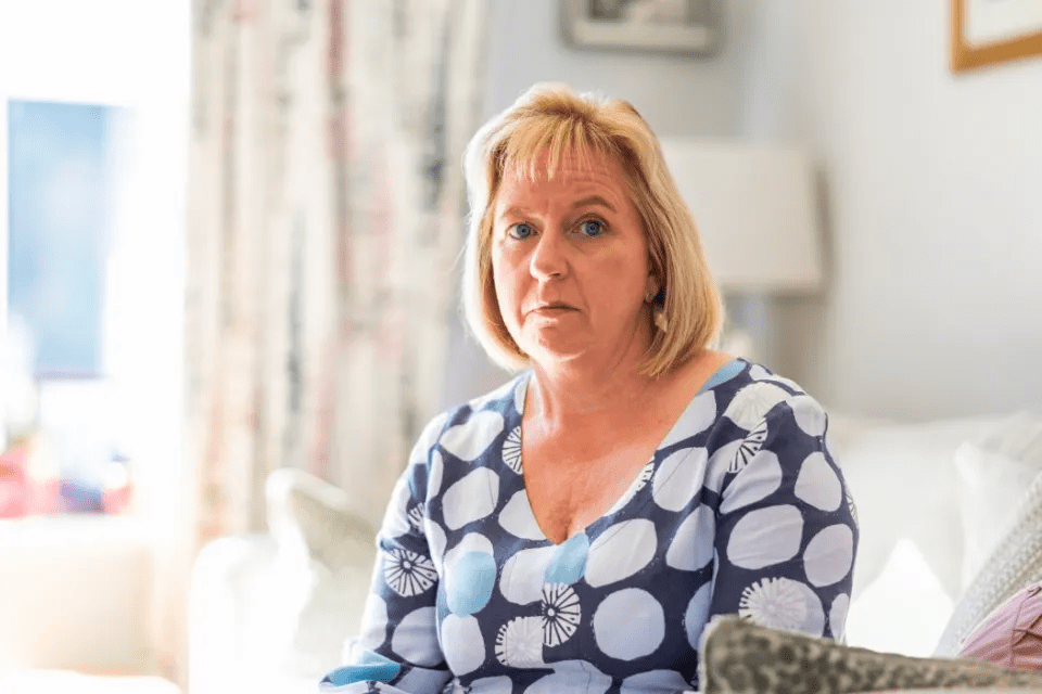 a woman in a blue and white polka dot shirt sits on a couch