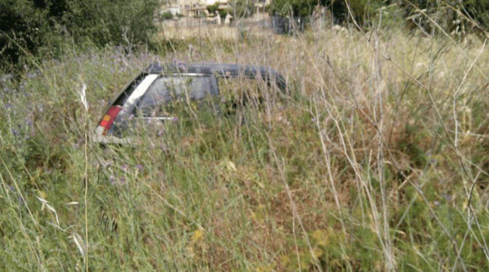 a car is laying in a field of tall grass