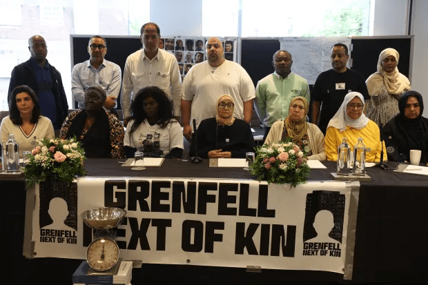 a group of people sitting at a table with a sign that says grenfell next of kin