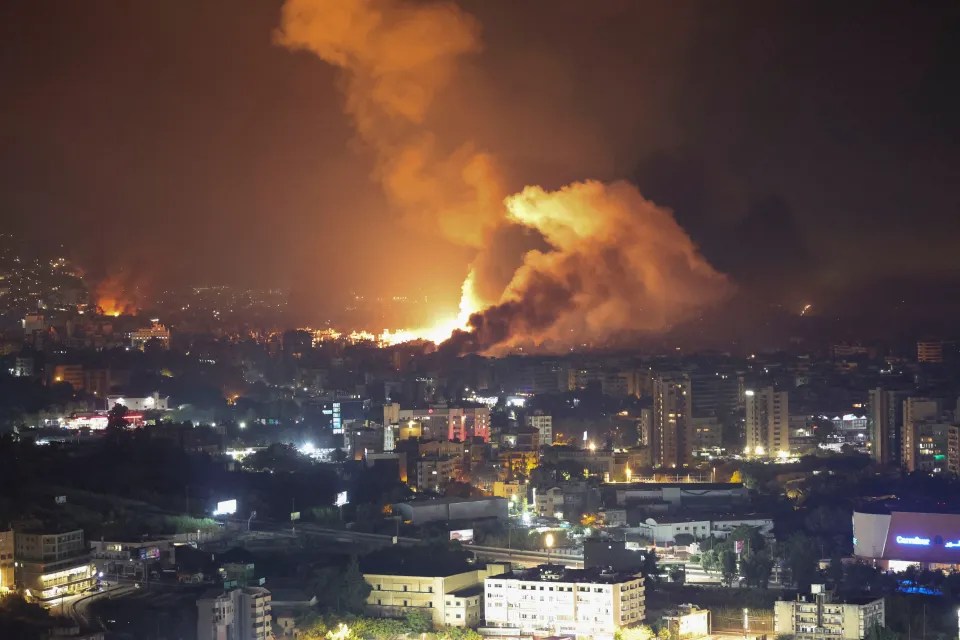 an aerial view of a city at night with smoke coming out of the sky
