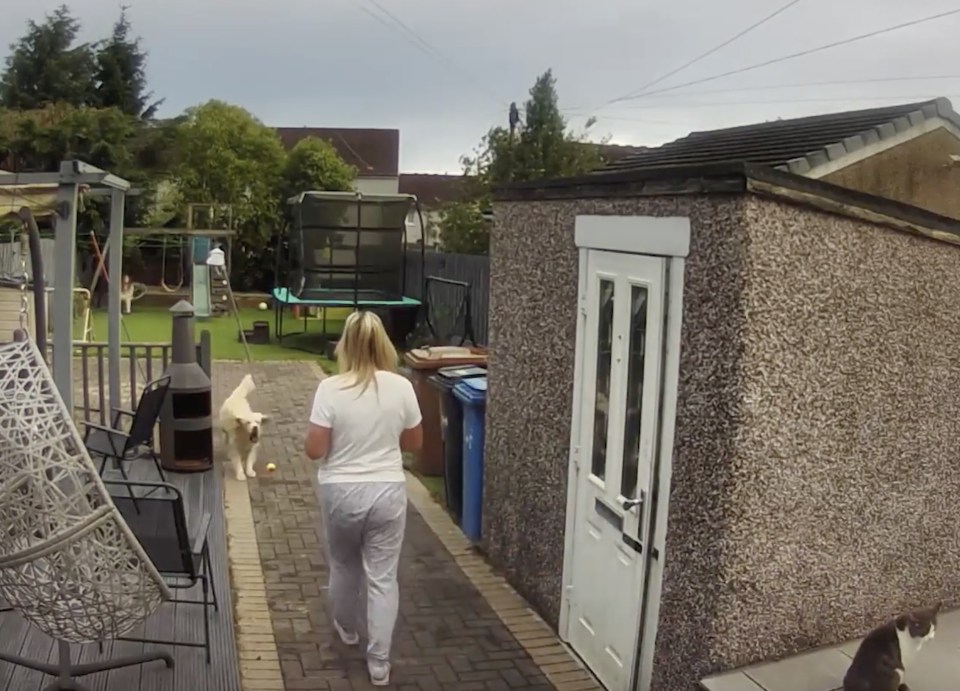 a woman walking down a sidewalk with a dog