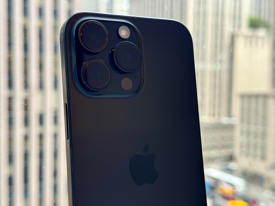 the back of a black apple iphone against a window