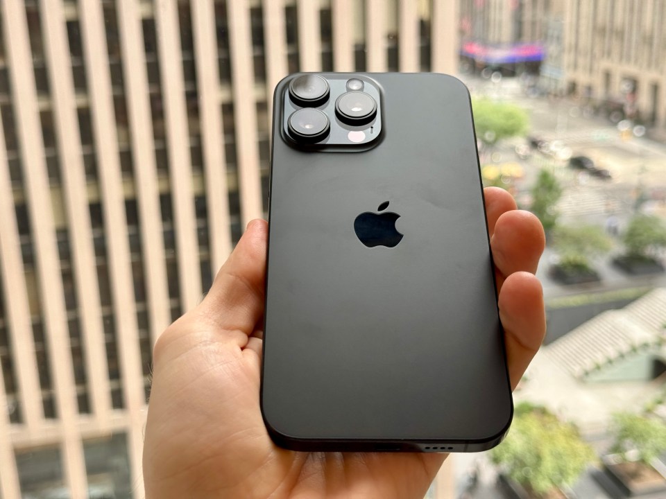 a person is holding a black iphone in their hand