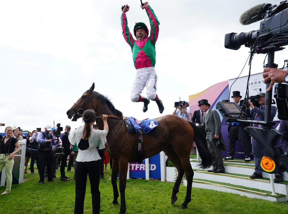 a jockey jumps in the air in front of a sign that says derby