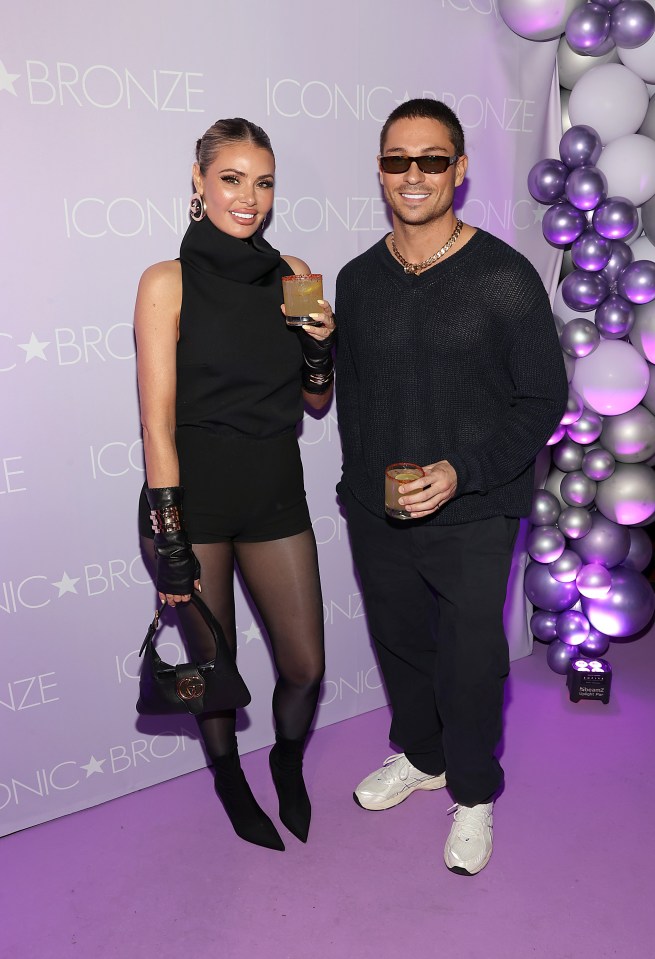 a man and a woman pose for a photo in front of a wall that says bronze
