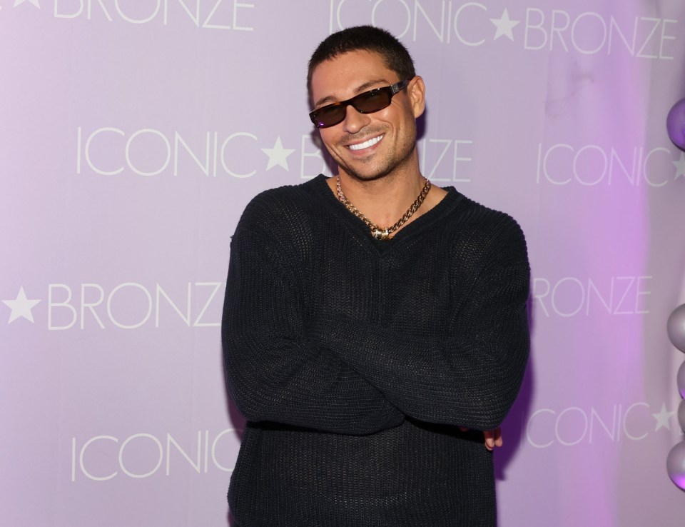 a man wearing sunglasses stands in front of a sign that says iconic bronze