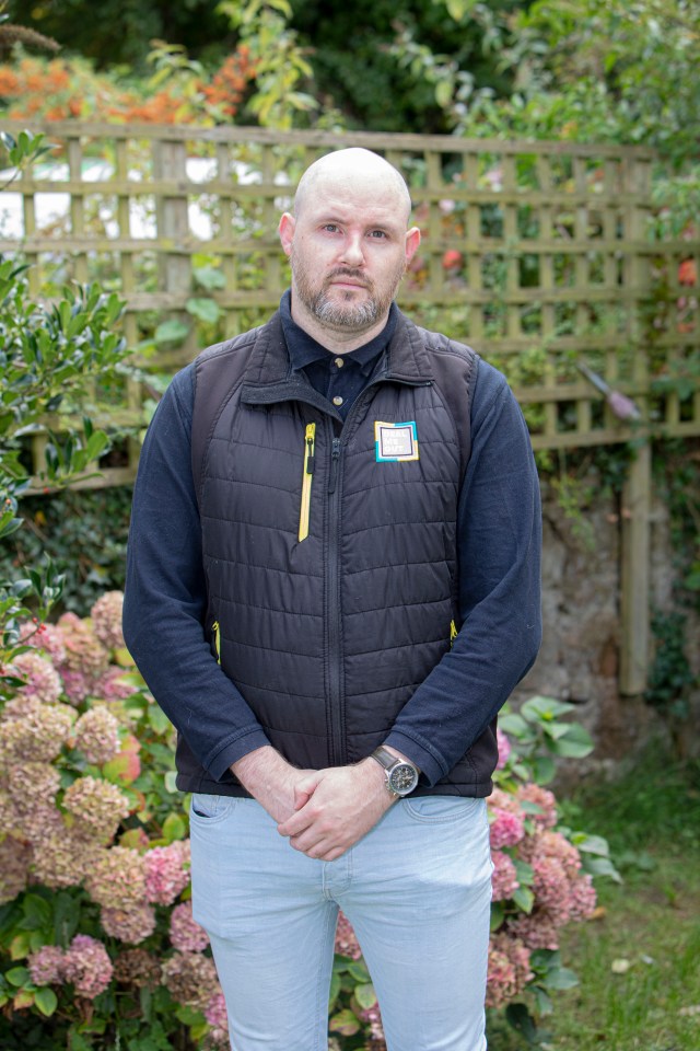 a man wearing a black vest with a yellow patch on it