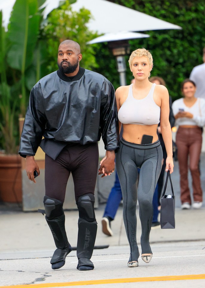 a man and a woman are walking down the street and the woman is wearing a crop top