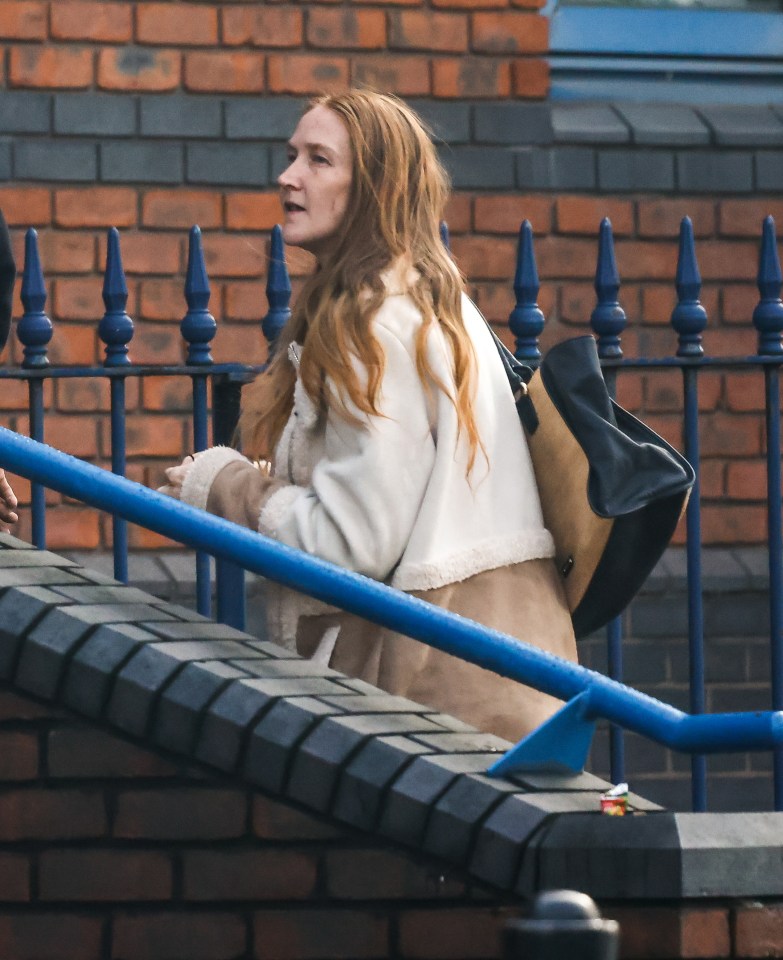 a woman with red hair is walking down a set of stairs