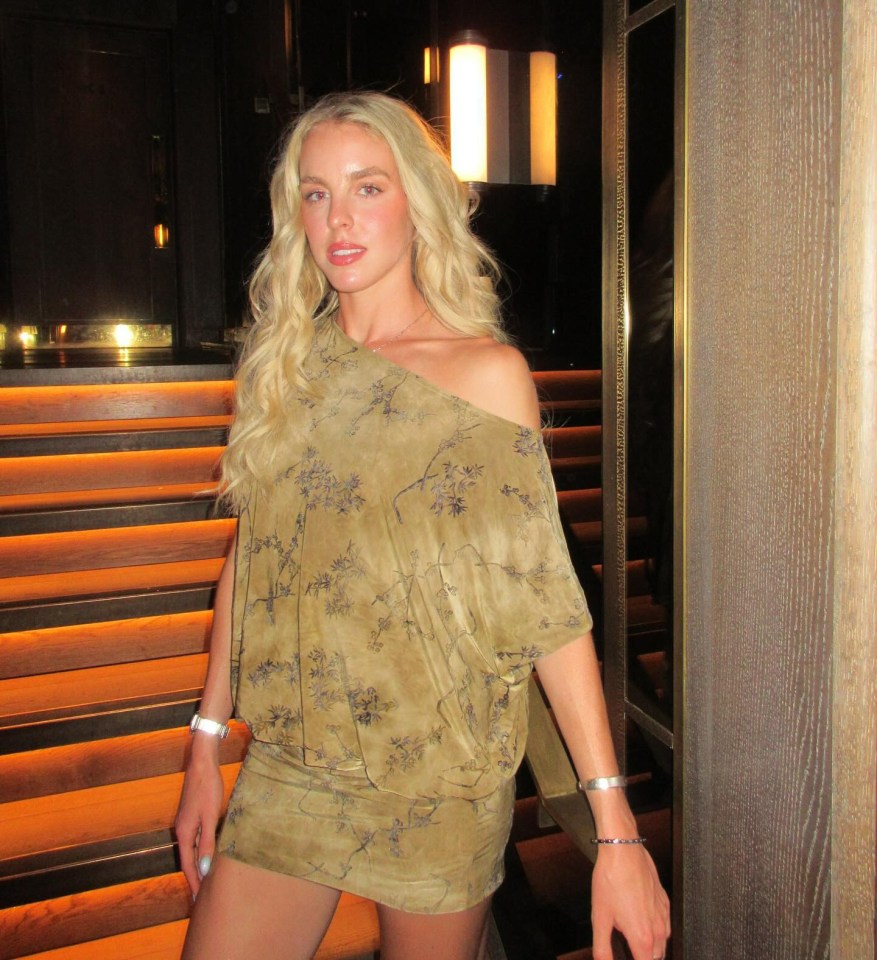 a woman in a green dress is standing in front of stairs