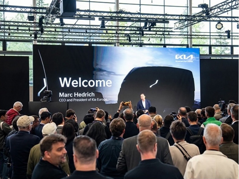 a man stands in front of a large screen that says welcome